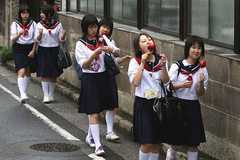 Estudantes japonesas andando e comendo maçã do amor